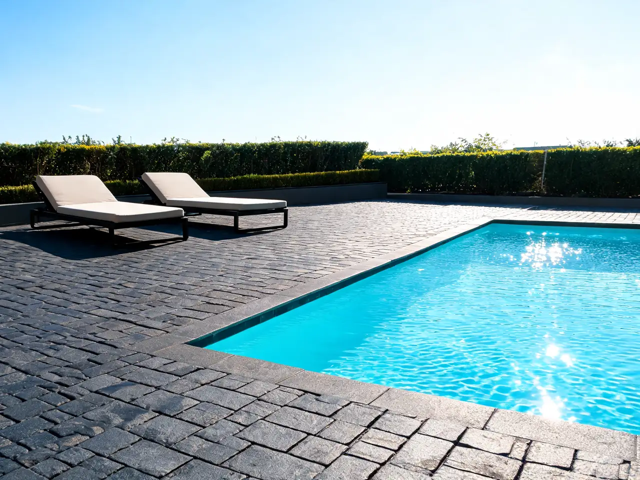 Dark charcoal paver pool deck idea contrasting with bright turquoise pool water