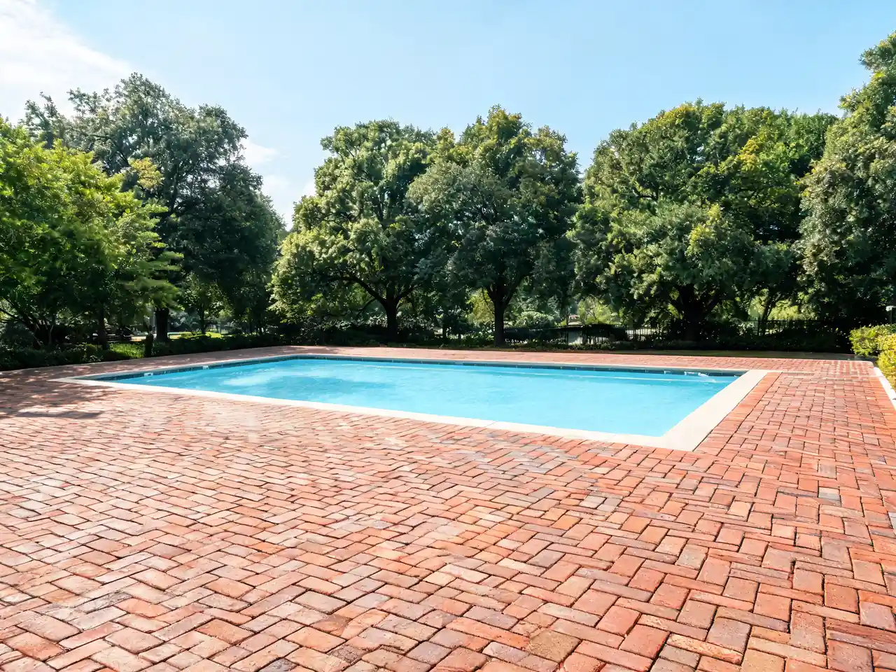 Brick paver pool deck idea in a herringbone pattern around a family pool