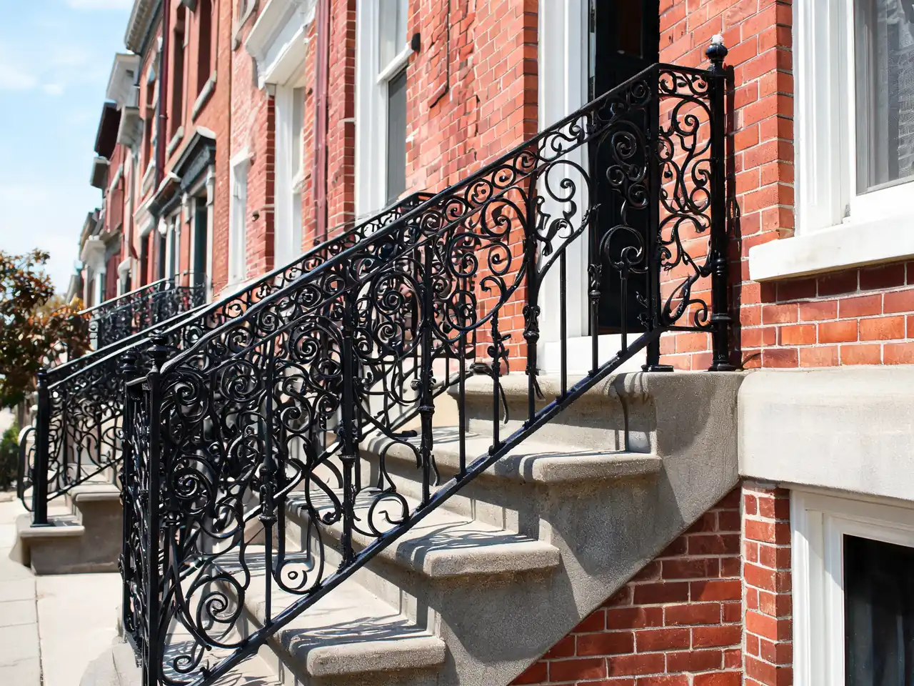 Ornate black wrought iron porch railing idea on brick front steps