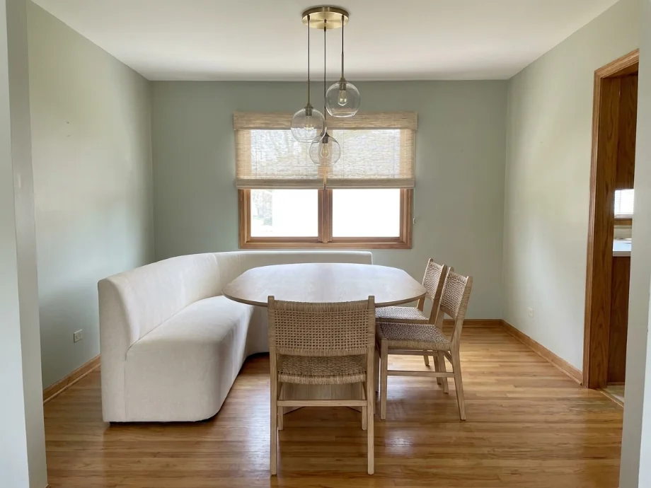 Dining room restyled with an oval table, a soft bench, and a pendant cluster. after AI redesign
