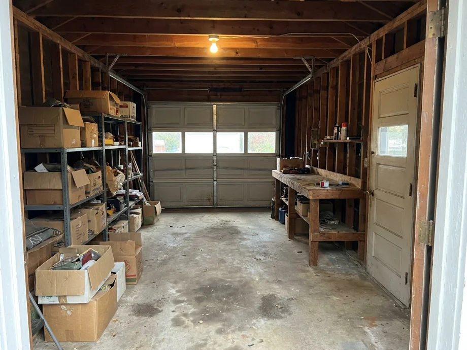 One-car garage restyled with wall shelving, a slatwall, and a folding workbench. before AI redesign