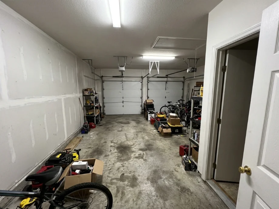 Two-car garage upgraded with an EV charger, overhead racks, and a tire rack. before AI redesign