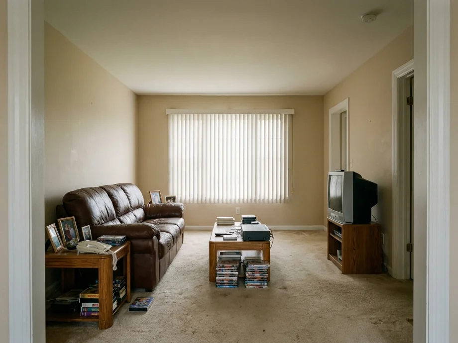 Living room restyled with a sectional, layered rug, and a media console. before AI redesign