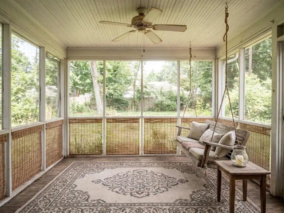 Screened porch refreshed with a hanging swing, a ceiling fan, and outdoor rugs. after AI redesign