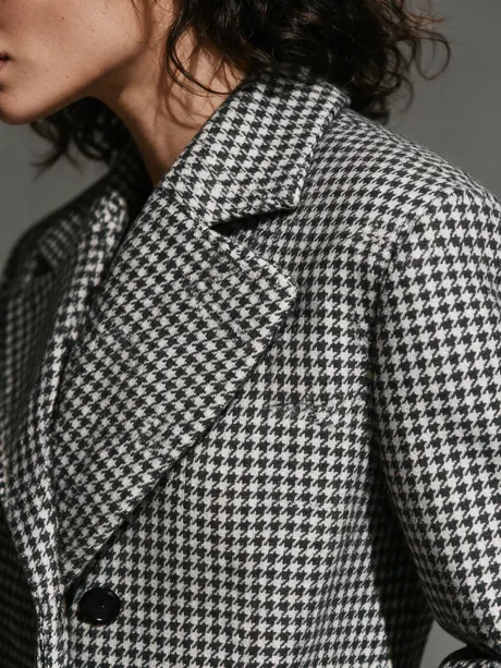 Close-up of the houndstooth coat lapel and weave on AI model Valentina