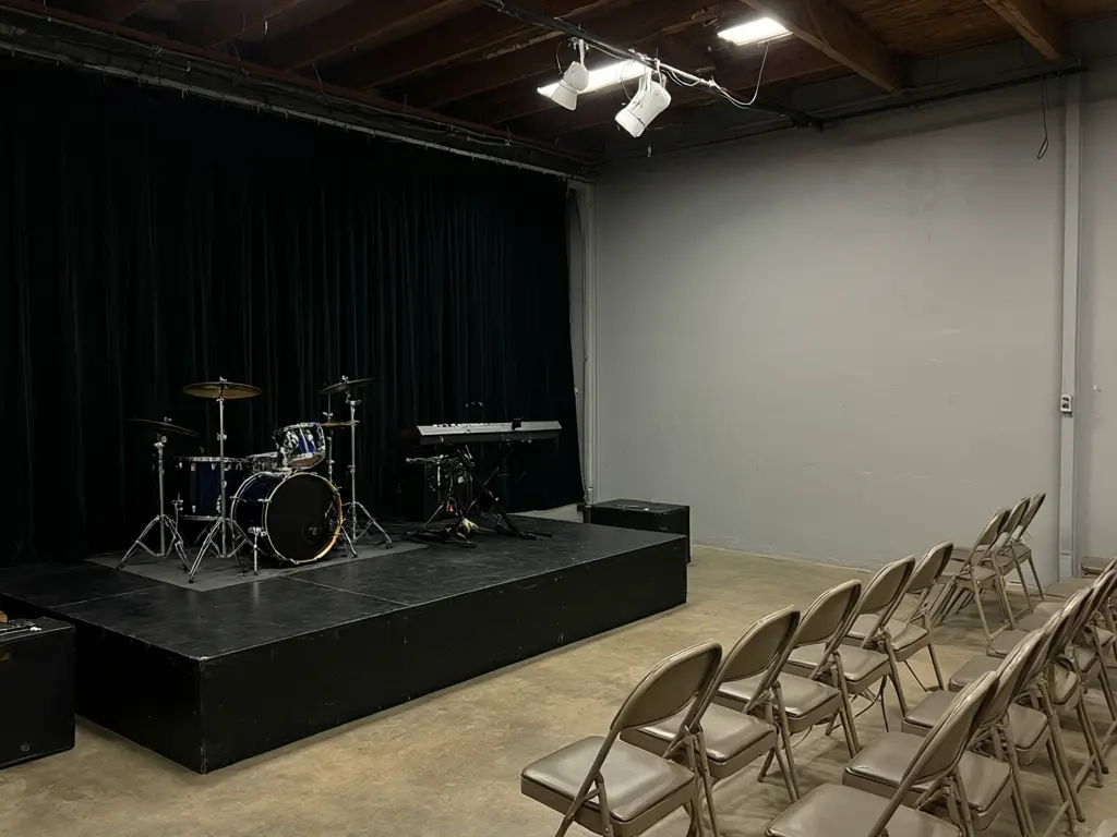 Church stage design ideas result: black curtained worship stage turned into a purple and blue lit hexagon panel wall with a centre screen, band and platform kept before AI redesign