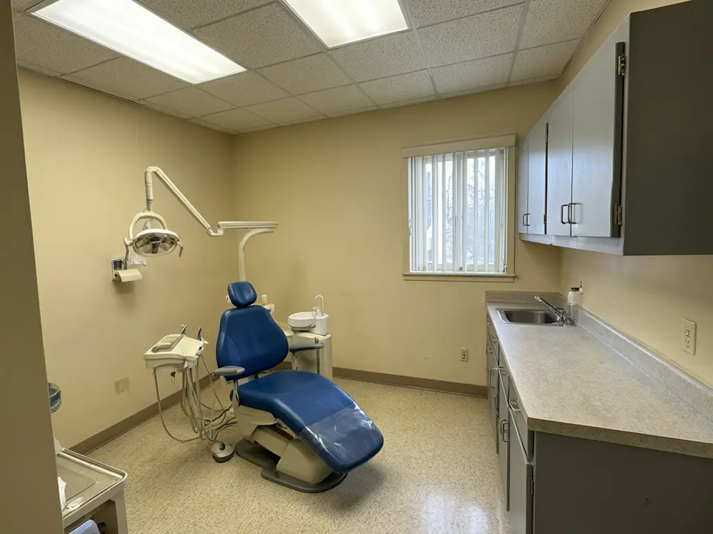 Dental office interior design result: dated beige treatment room refitted with an oak slat feature wall, a backlit sky ceiling panel above the chair, warm cove lighting, oak cabinets and a pale wood floor, with the same dental chair before AI redesign