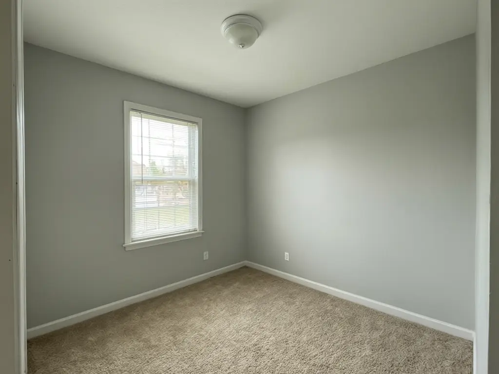 Home photography studio design result: plain grey spare room turned into a moody dark studio with black walls and ceiling, a grey backdrop wall, black velvet curtains, a ceiling track with spotlights and a dark floor before AI redesign