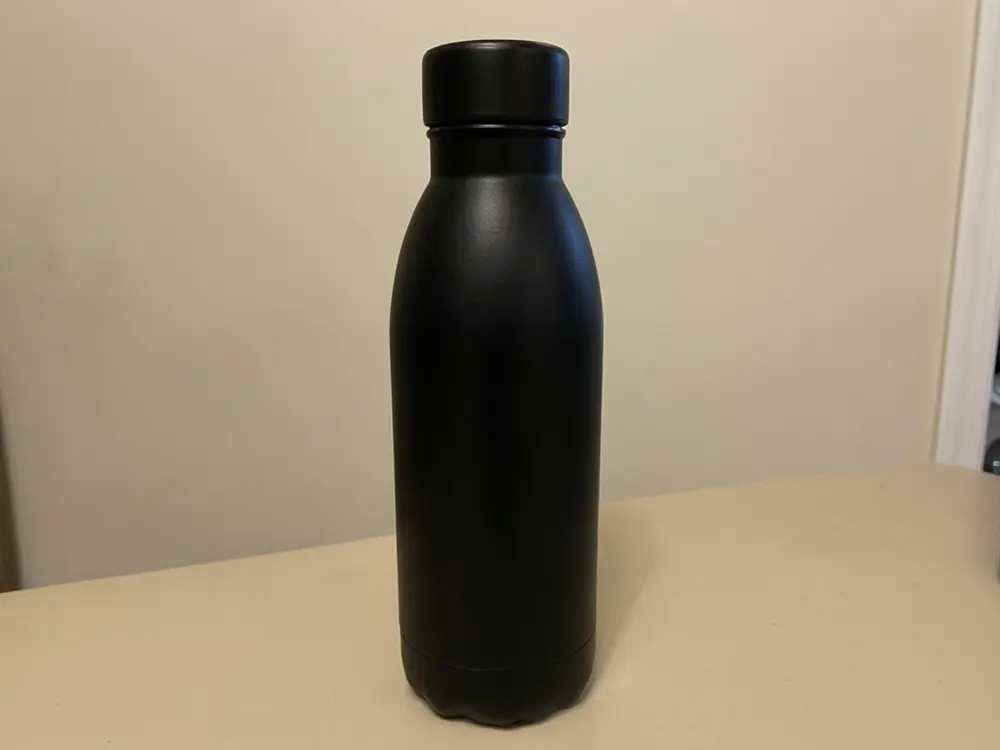 Product photo background result: stainless steel water bottle on a plain table placed on a marble kitchen counter before AI redesign