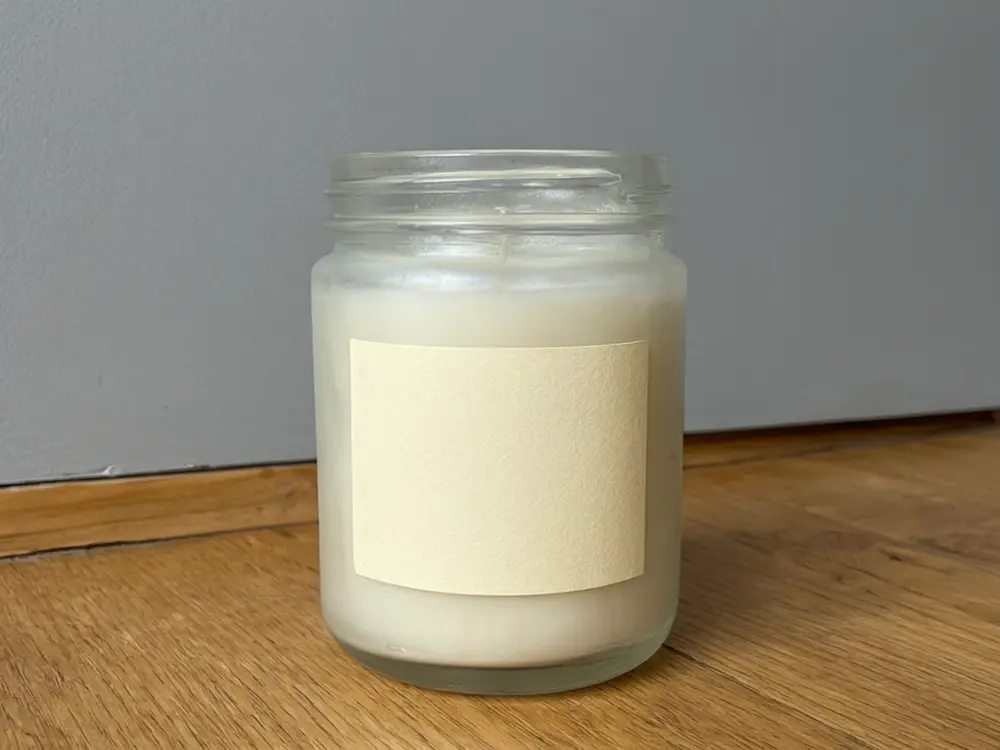 Product photo background result: handmade candle placed on a marble surface with soft light before AI redesign