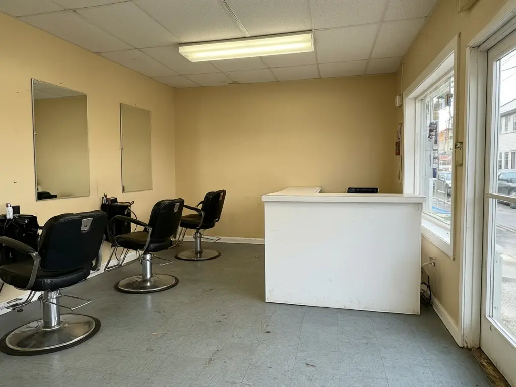 Salon interior visualizer result: plain hair salon restyled with arched brass mirrors, cognac leather styling chairs, a fluted reception desk and herringbone wood floor, stations kept in place before AI redesign