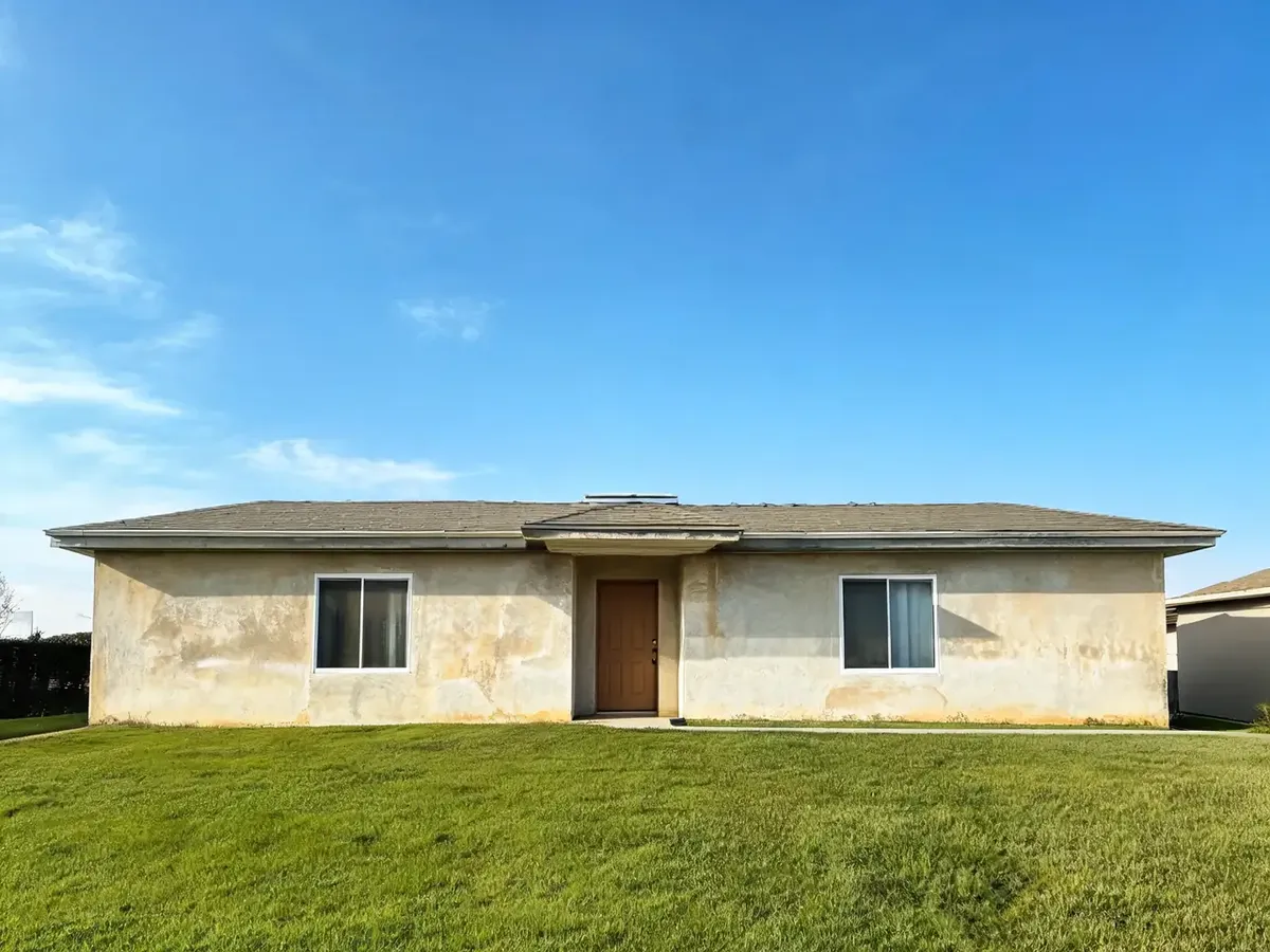 Stone veneer visualizer result: whole front wall of a stucco house covered in brown and rust fieldstone veneer, windows, door and roof unchanged before AI redesign