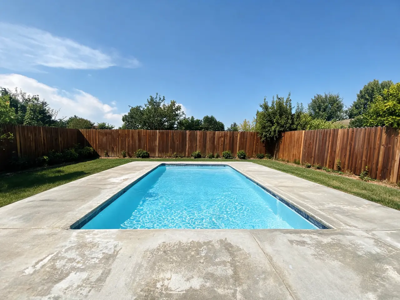 Pool deck visualizer result: worn concrete pool deck replaced with light beige travertine pavers before AI redesign