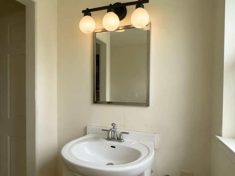 Light fixture visualizer result: a black three-light vanity fixture over a bathroom mirror after AI redesign