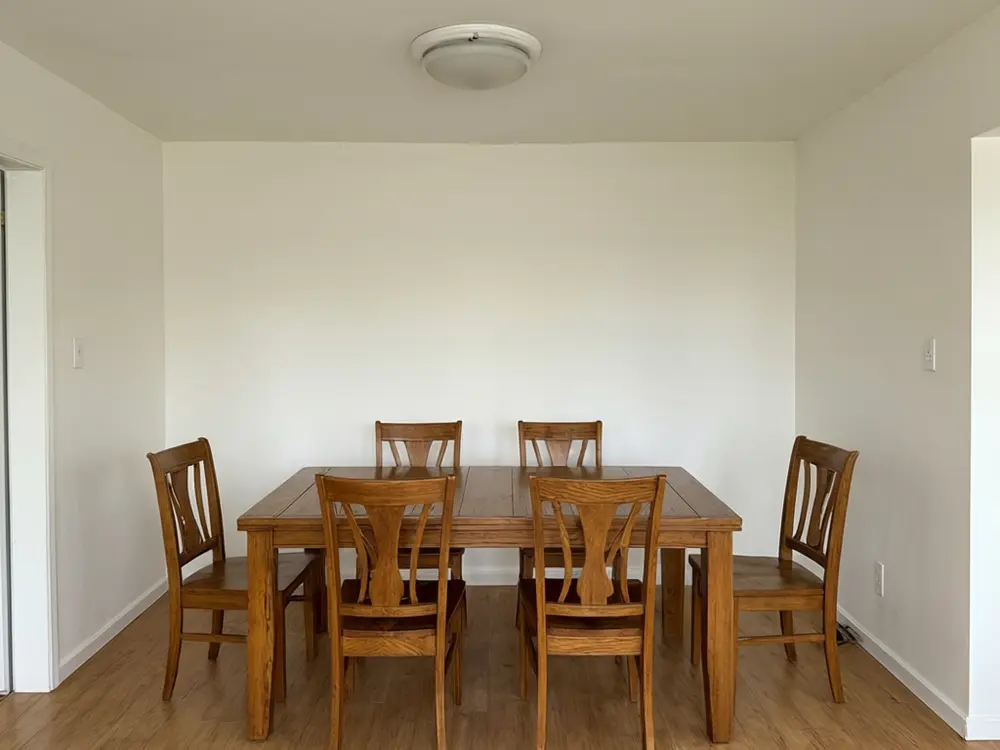 Light fixture visualizer result: a black modern linear chandelier over a dining table before AI redesign