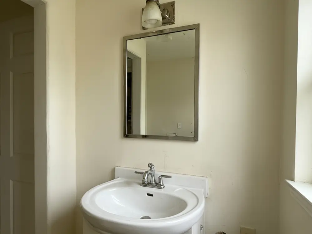 Light fixture visualizer result: a black three-light vanity fixture over a bathroom mirror before AI redesign