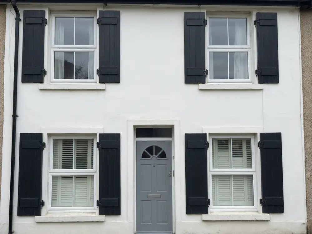 Shutter visualizer result: black board and batten shutters added to a white house after AI redesign